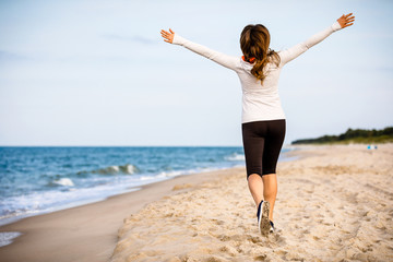 Obraz premium Young woman running, jumping on beach