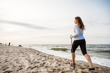 Nordic walking - young woman working out on beach