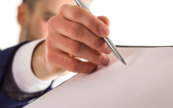 Male hand holds pen near paper document, close up.