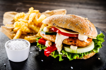 Tasty cheeseburger with french fries served on fashionable black desk