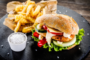 Tasty cheeseburger with french fries served on fashionable black desk