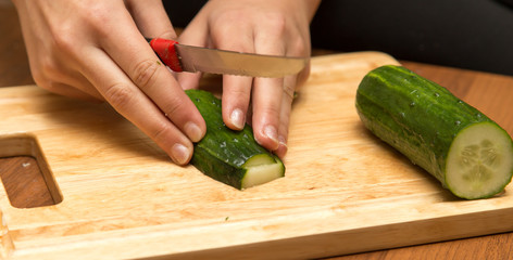 Slicing cucumber with a knife on the board