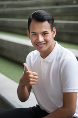 happy man giving thumb up gesture; smiling friendly man showing approval, agreed thumb up; happy smiling man shows thumb up hand sign concept of agreement, ok, yes, good; young adult asian man model