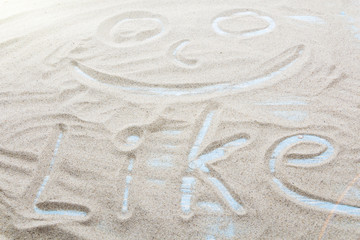 Fototapeta na wymiar Handwritten word LIKE on brown sand on the beach in sunny day.