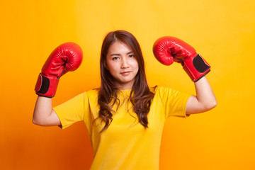 Young Asian woman with red boxing gloves in yellow dress