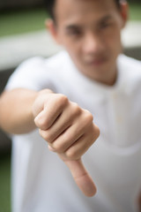 rejecting man showing thumb down gesture; man denying with thumb down, concept of deny, rejection, turn down, negative feedback, bad, no; asian young adult man model