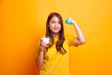 Healthy Asian woman drinking a glass of milk and dumbbell in yellow dress