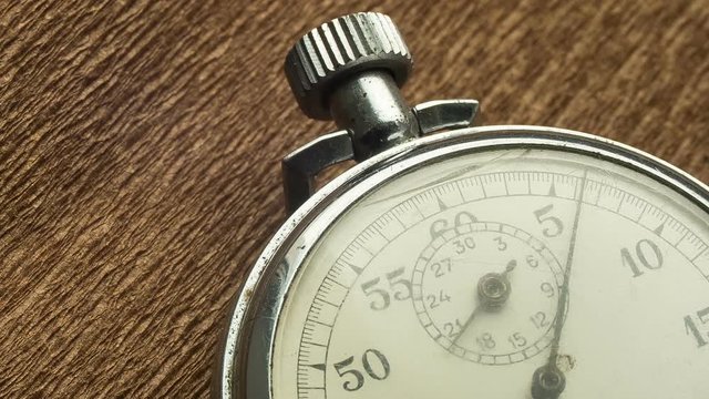 Vintage White Stopwatch on the Brown Structural Background Rotates the Arrow. Time lapse. Stopwatch Clock Face. Close Up. Dial Hands, Minutes Hours Seconds. Macro Shot. The second hand on the dial