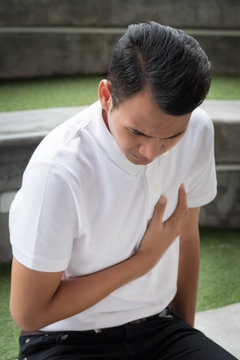 man with heart attack; sick asian man suffering from heart attack or seizure; young adult asian man model, dangerous acute heart attack health care concept