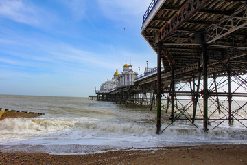View of an English pier and its structure, from the beach with the tide going out