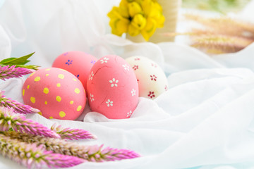 Happy easter! Colorful of Easter eggs in nest with flower,  paper star and Feather on white cheesecloth background.