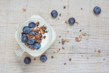Natural yogurt with granola, berries  on the wooden table top view selective focus