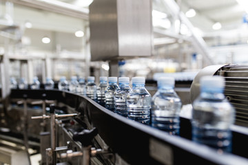 Water factory - Water bottling line for processing and bottling pure spring water into small blue bottles. Selective focus. 