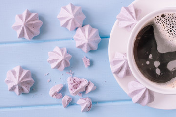 Pink meringue and a cup of coffee on a blue background. Pastel colors.