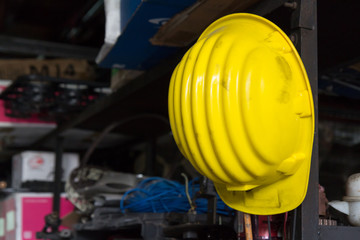 Fototapeta premium dirty yellow safety helmet hangs on steel shelf in warehouse of factory. safety equipment.