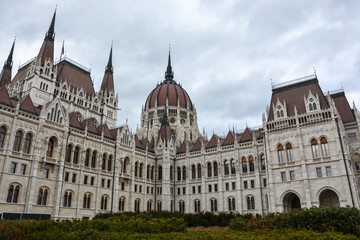Fototapeta na wymiar Budapest parliament with bushes in front with cloudy sky