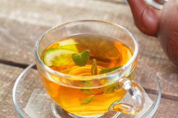 cup of black tea with mint leaves on a wooden table