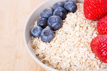 A bowl of oatmeal with fresh strawberries on wooden table