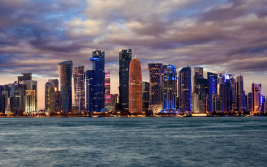 Fototapeta premium Die beleuchtete Skyline von Doha, Katar, nach Sonnenuntergang mit bewölktem Himmel