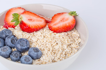 A bowl of oatmeal with fresh strawberries on white background