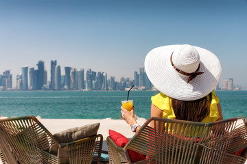 Attraktive Touristin genießt die Aussicht auf Doha in Katar bei einem erfrischenden Orangensaft