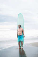 Fototapeta na wymiar shirtless surfer standing with surfboard in Bali, Indonesia