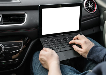 The man is operating a computer in a car