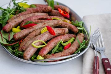 Grilled sausages with vegetables, fresh herbs and spices on white background.