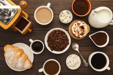 Various coffee cups and sweet pastry on vintage wooden table, top view
