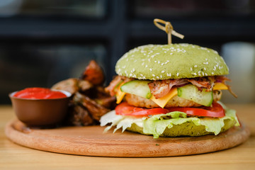 Close-up of delicious home made chicken burger on the wooden board, served with tomato sauce.
