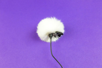 Miniature microphone of the buttonhole. A small microphone for recording high-quality sound on a purple background.