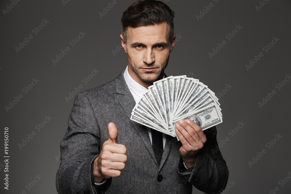 Canvas Prints photo of rich man 30s in business suit holding fan of cash money dollar currency and showing thumb u