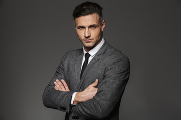 Portrait of businessman wearing formal costume and looking on camera with serious gaze, isolated...