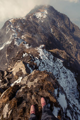 Legs of traveler hiker staying in fog on high snow mountain top in travel. Freedom concept