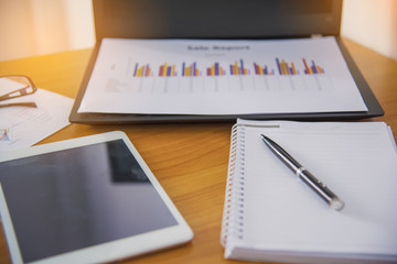 Laptop with financial documents on wooden table