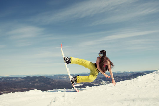 Portrait of happy young snowboarder female jumping on snowboard with waving hair. Sunny winter holiday, winter sport outdoor, free people