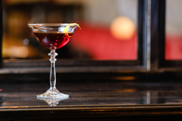 Beautiful tall glass of cocktail in front of the mirror on the wooden table.