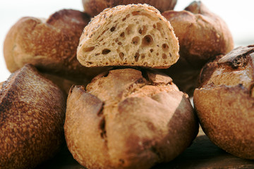 Loaves of homemade bread with one sliced bun.