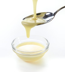closeup pouring condensed milk with teaspoon