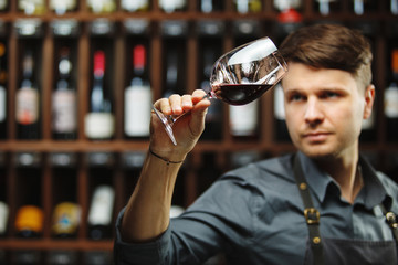 Bokal of red wine on background, male sommelier appreciating drink