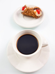 White cup of hot coffee or espresso coffee with sweet sicilian dessert (cannoli) in italian style in white background.