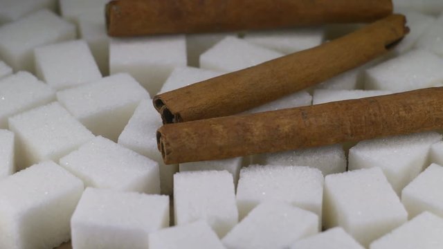 Shugar cubes with sticks of cinnamon close up on rotating table