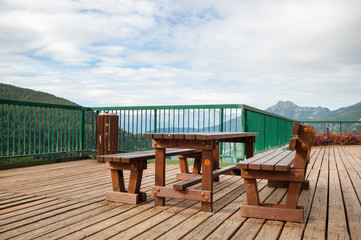 Outdoor wood bench chair and wood table on wood floor in the balcony with mountain landscape in summer natural background.