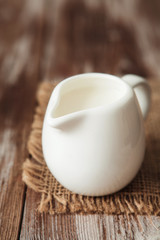 Obraz na płótnie Canvas Fresh milk in jug on the wooden table for breakfast