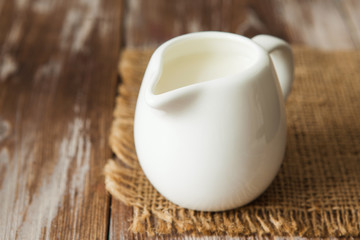 Fresh milk in jug on the wooden table for breakfast