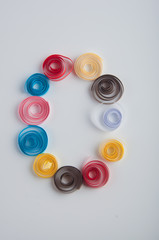 Letter O made of red, pink, blue, yellow, white, brown paper quilling spirals