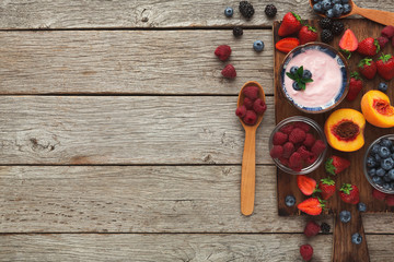 Yogurt, fruits and berries on rustic wood, top view