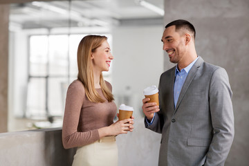 business, people and corporate concept - happy smiling businesswoman and businessman drinking coffee at office