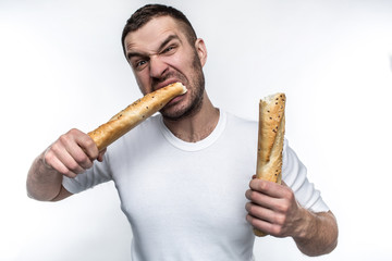 Very hungry man is starving. He broke a long piece of baguette into two pieces. He is eating one of...