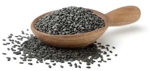 black sesame seeds in the wooden spoon, isolated on white